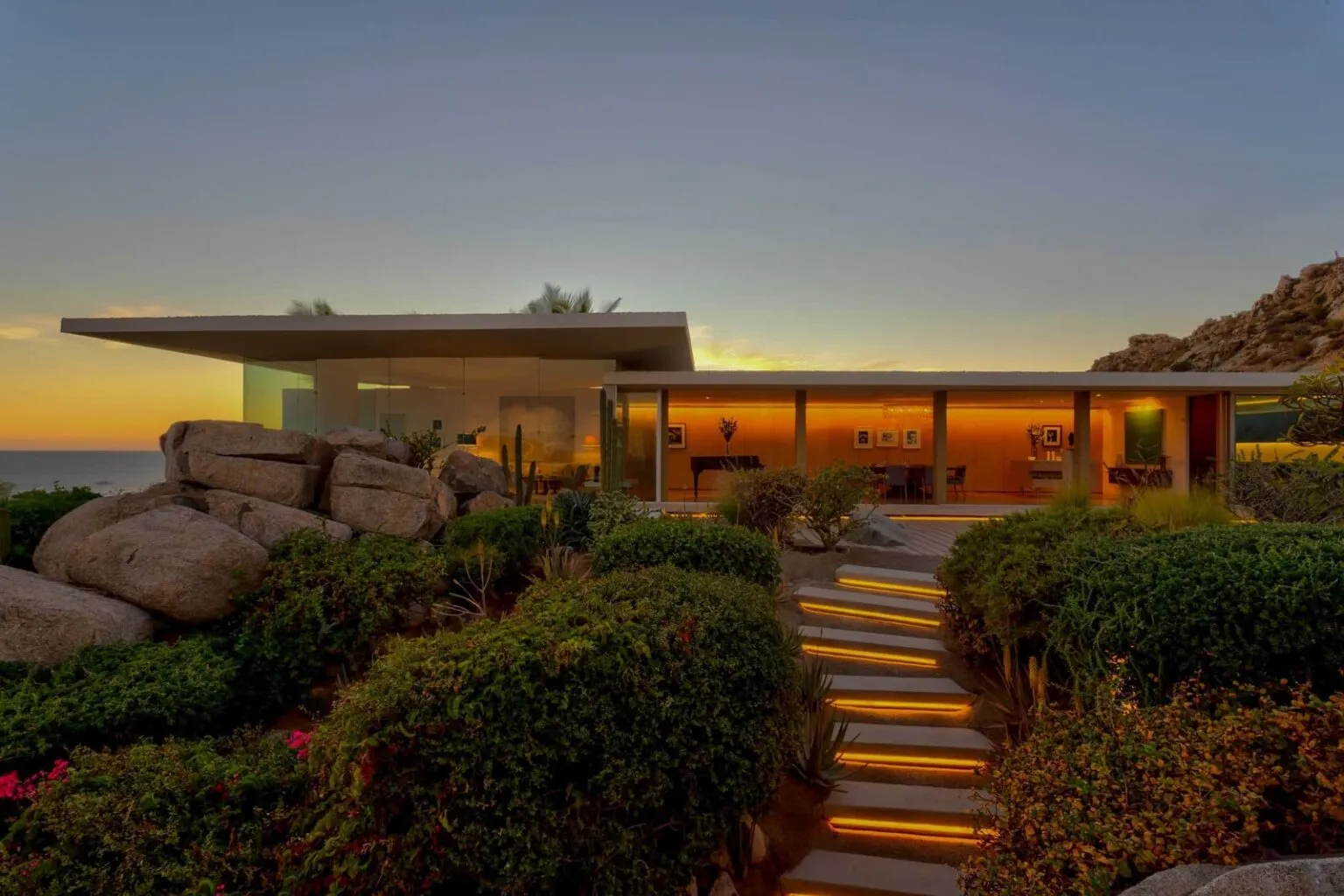Casa Finisterra Pedregal modern villa with landscaped gardens, illuminated steps, and sunset views