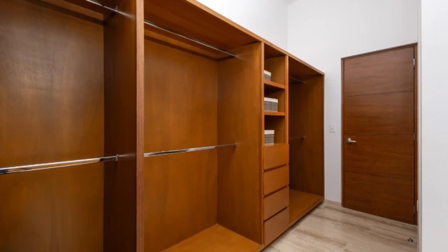 amplio vestidor madera dunas condo Spacious wooden walk-in closet with drawers, shelves, and hanging rods in a vacation condo.