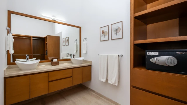 bano doble lavabo caja fuerte dunas condo Double sink area with a large wood-framed mirror and open shelving including a safe.