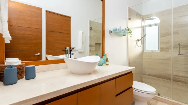 bano moderno lavabo dunas condo Modern bathroom with a designer sink, wooden vanity, large mirror, and glass-enclosed shower.