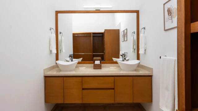 bano principal espejo dunas condo Master bathroom with white vessel sinks, wooden drawers, and a large rectangular mirror.