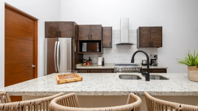 cocina departamento vacacional dunas condo Kitchen detail with a refrigerator, stove, microwave, and a breakfast bar with a sink.