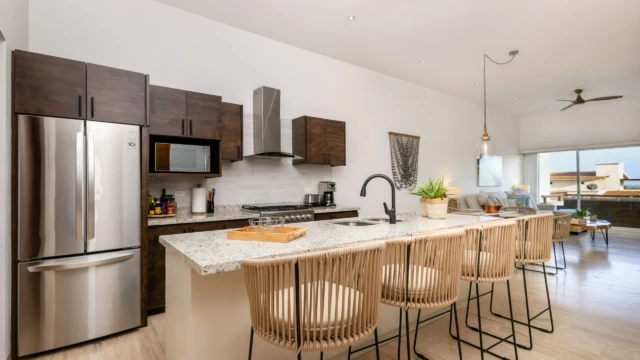 cocina equipada isla dunas condo Open layout kitchen with a granite island, rope bar stools, and stainless steel appliances.