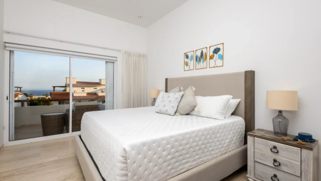 habitacion cama king renta dunas condo Master bedroom with a gray headboard, rustic nightstand, and direct access to a balcony with a view.