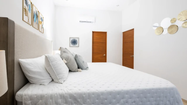 recamara aire acondicionado dunas condo Bedroom detail showing a comfortable bed, air conditioning, wall decor, and wooden doors.