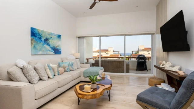 sala estar balcon dunas condo Bright living room with an L-shaped sofa, natural wood coffee table, television, and a balcony with a view.