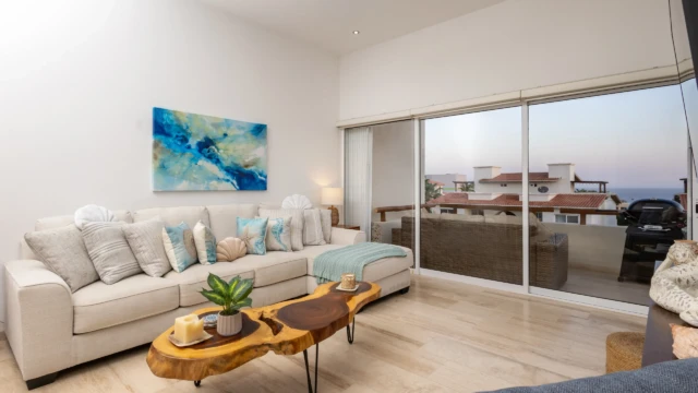 sala estar dunas condo cabo Bright living room with an L-shaped sofa, rustic table, and balcony access at Dunas Condo.
