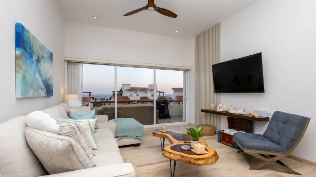 sala tv terraza renta vacacional TV room with a comfortable sofa, blue chair, rustic coffee table, and access to an outdoor terrace.